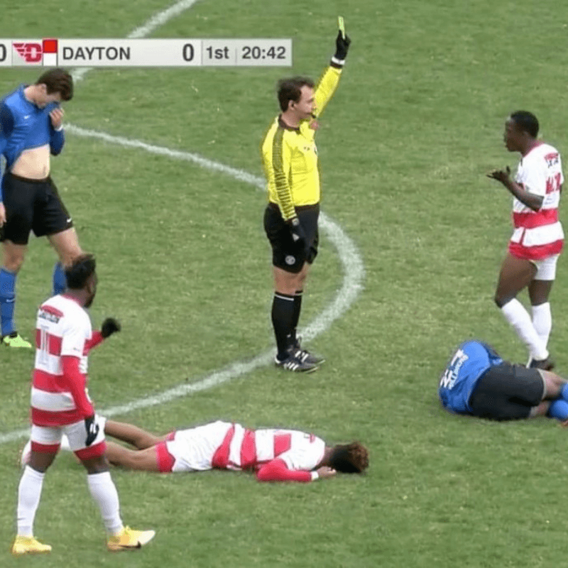 Favorite Things About Fall - Referee on Soccer Field with Arm Raised and Players Standing and Laying on Ground